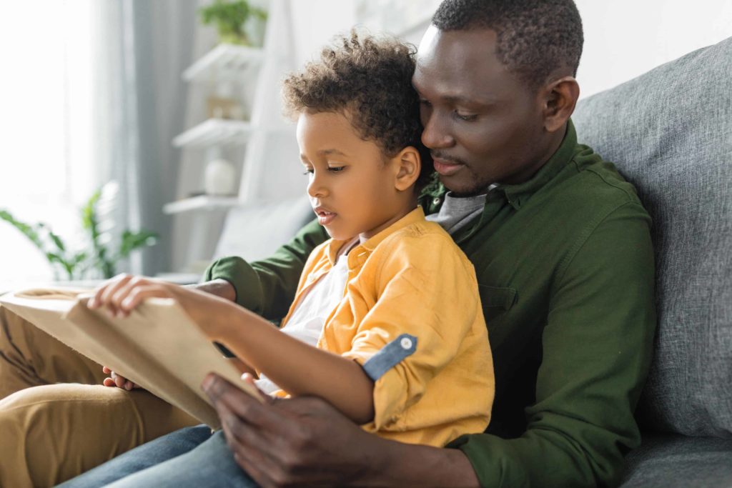 cute african-american father and son reading book together